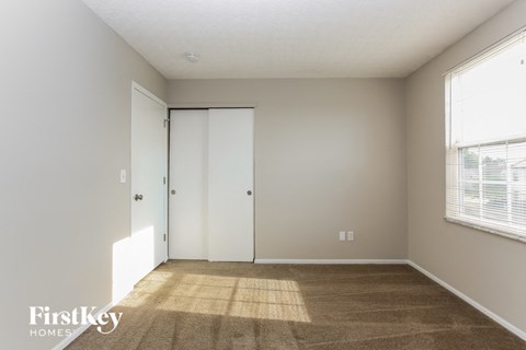a living room with a carpet and a door to a closet