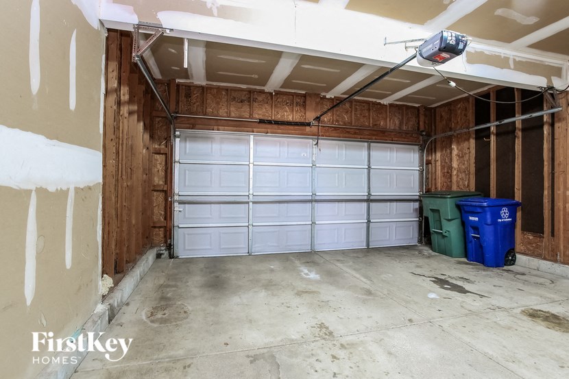 a garage with two white garage doors and two garbage cans