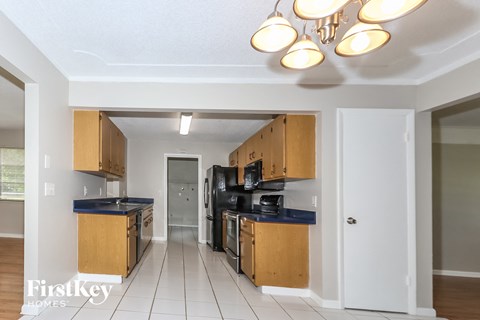 a kitchen with wooden cabinets and black appliances and a hallway with a door
