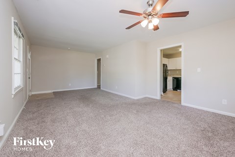 a spacious living room with carpet and a ceiling fan