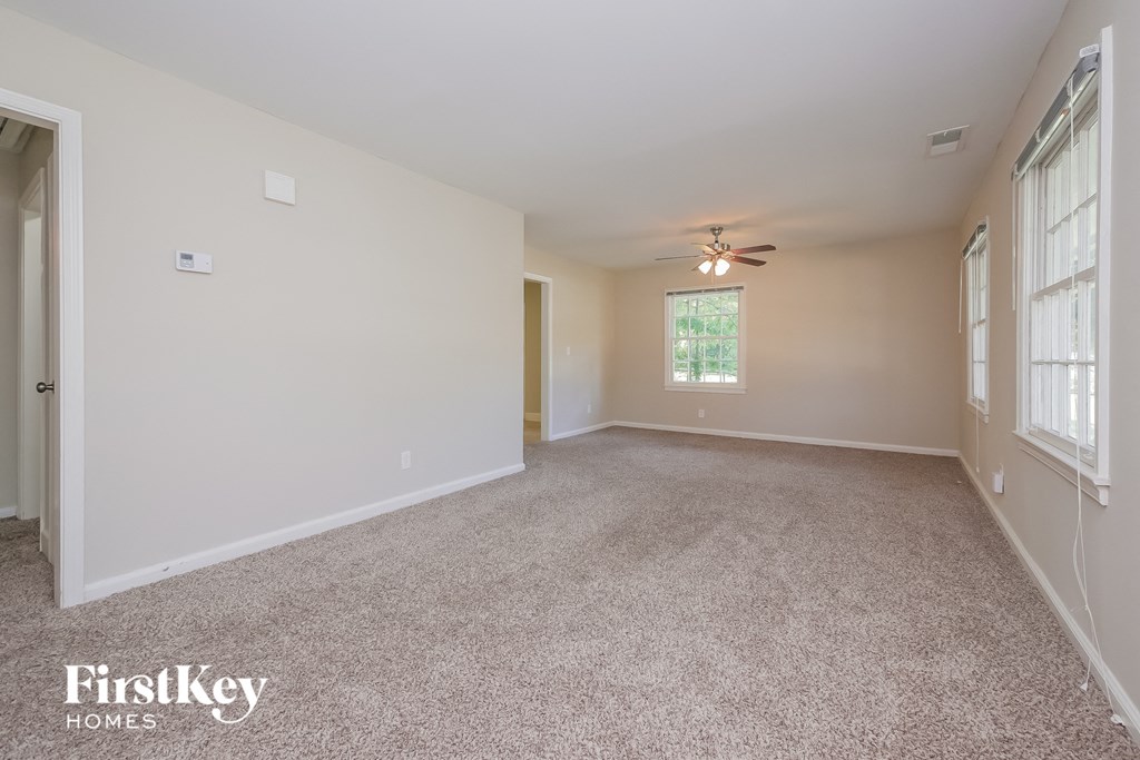 a spacious living room with carpet and a ceiling fan