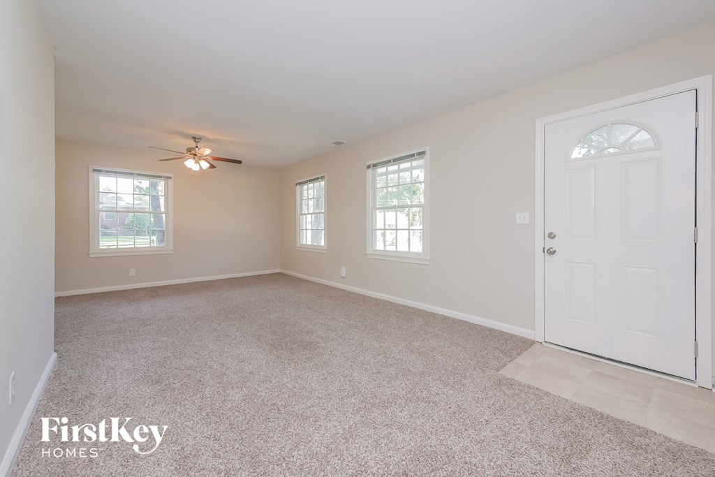 an empty living room with a white door and a ceiling fan