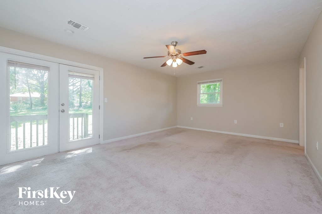 an empty living room with a ceiling fan and glass doors
