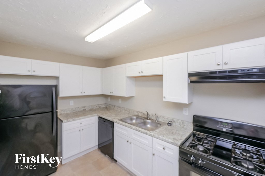 a kitchen with white cabinets and black appliances and a sink