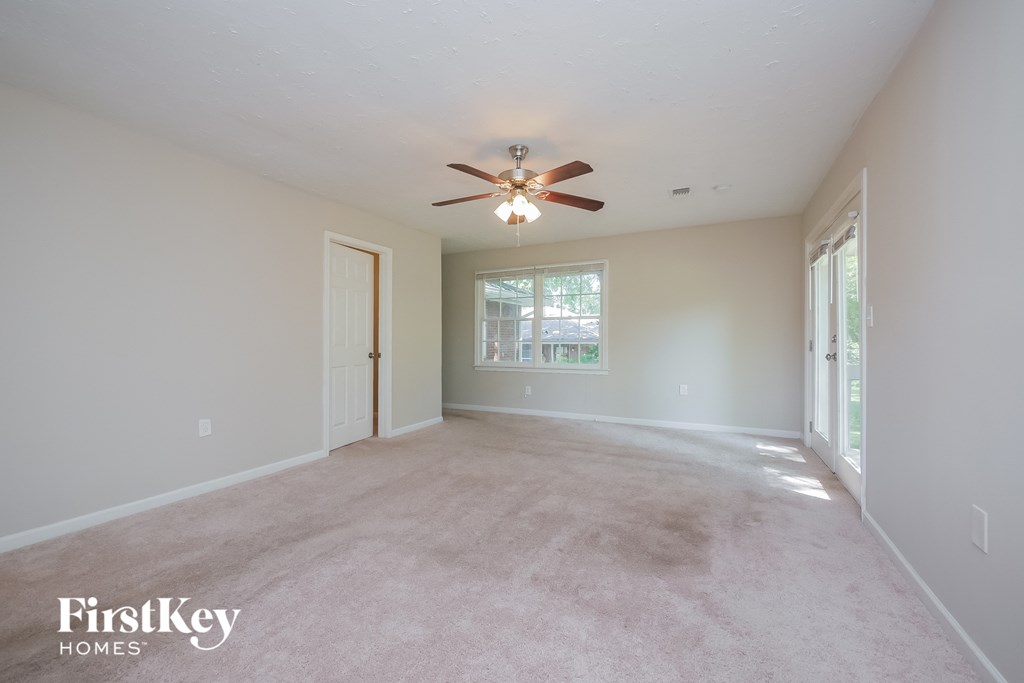 an empty living room with a ceiling fan and a window