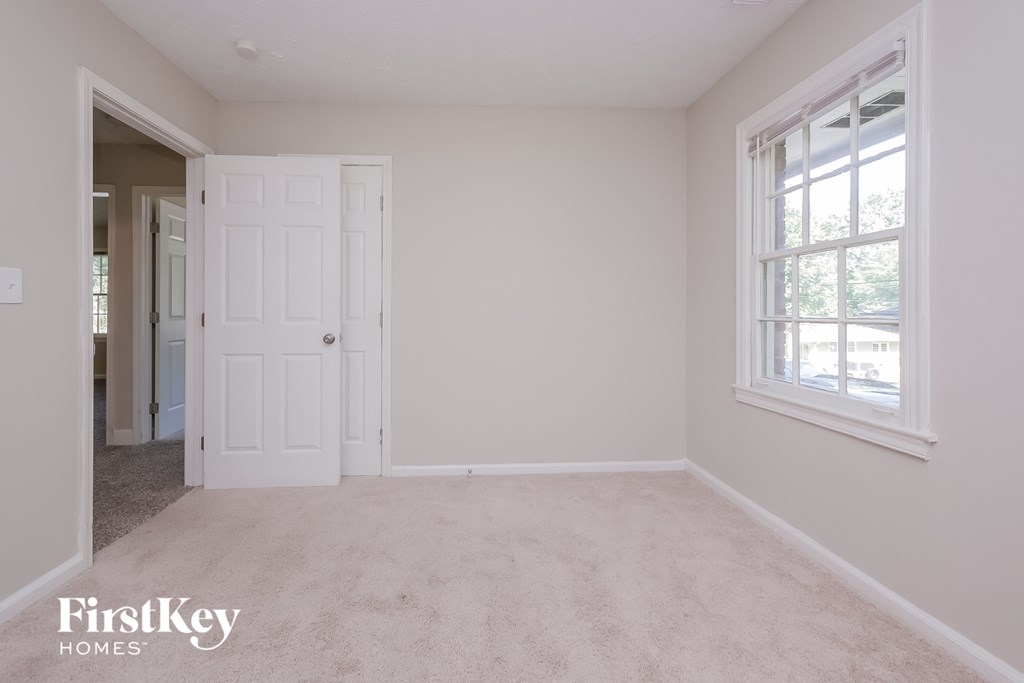 a bedroom with a carpeted floor and a white door and window