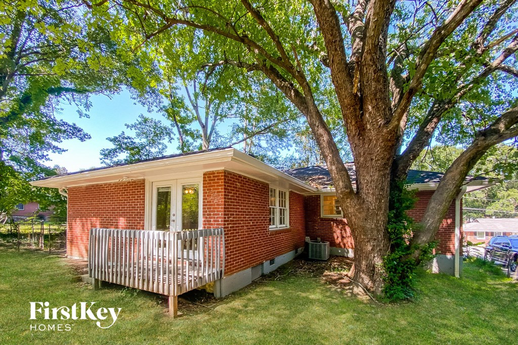 a small brick house with a porch and a tree