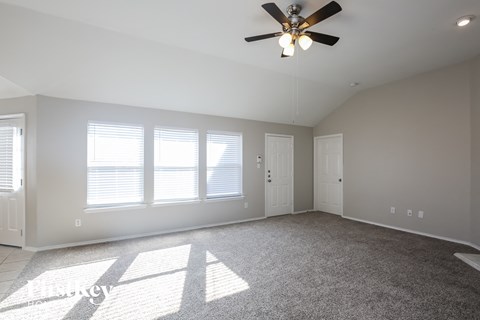 an empty living room with a ceiling fan and window