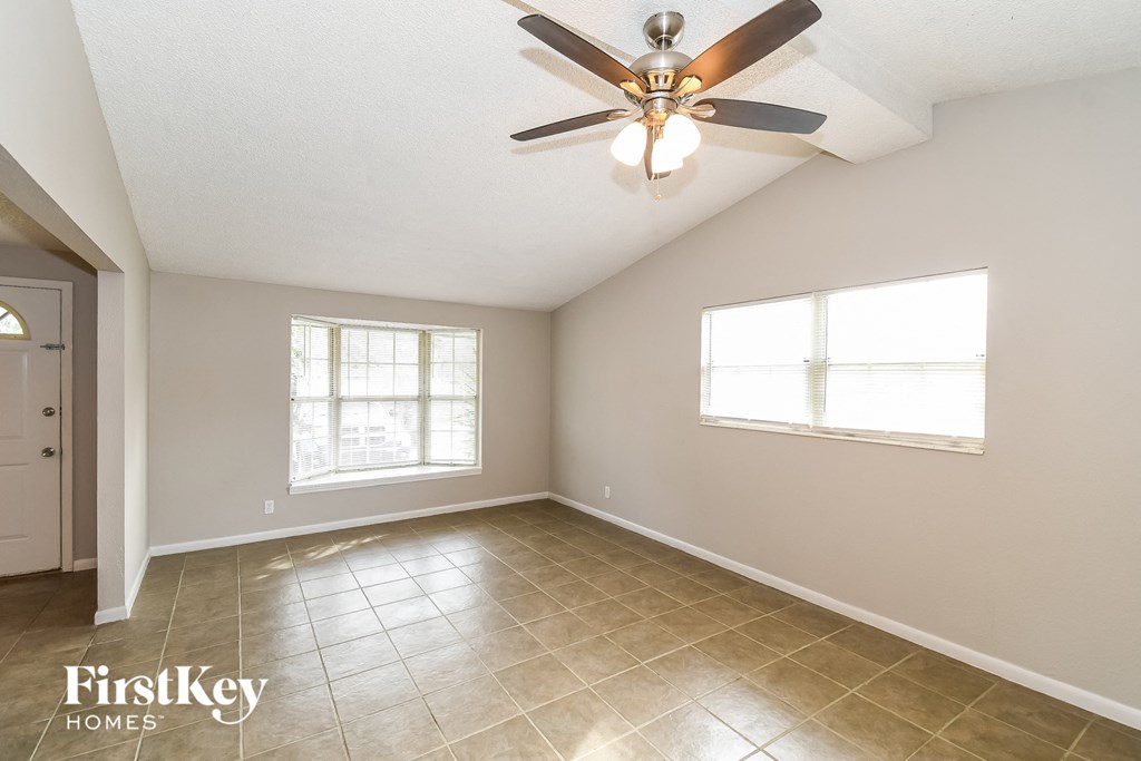 an empty living room with a ceiling fan and a window