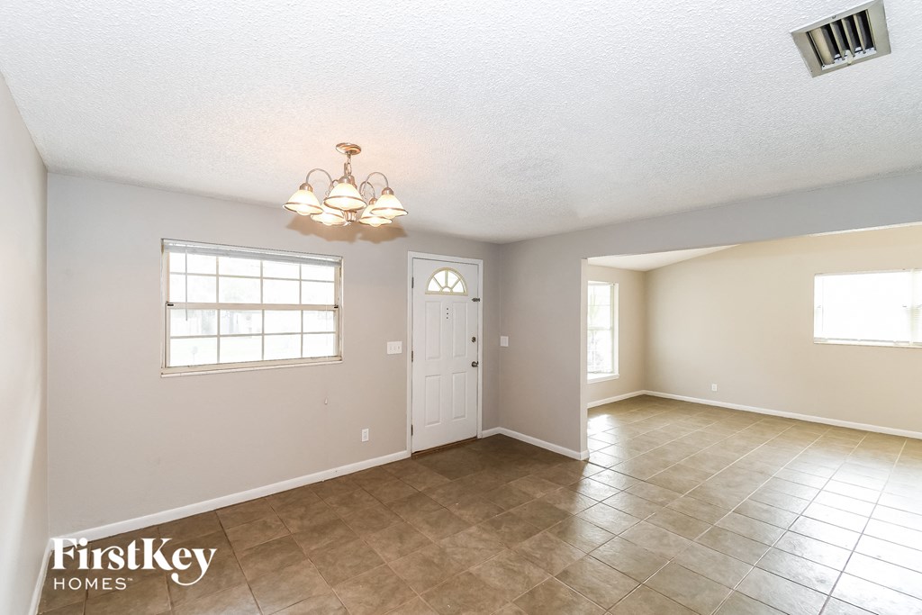 the living room and dining room with a white door and tile floor