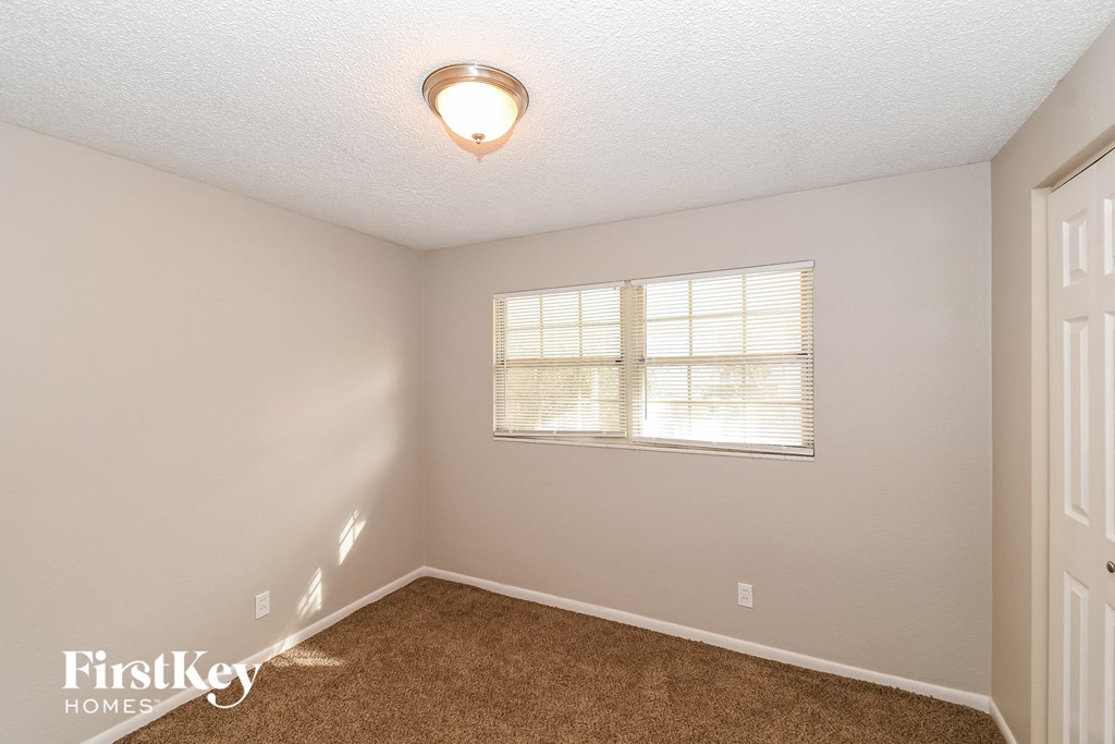 a bedroom with a window and a carpeted floor