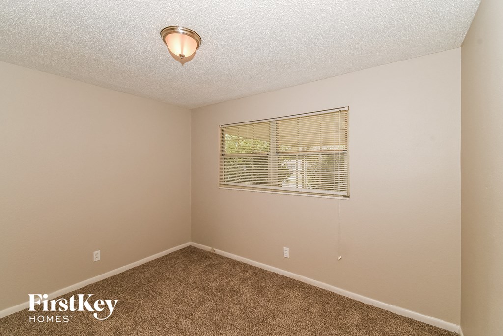 a bedroom with a window and a carpeted floor