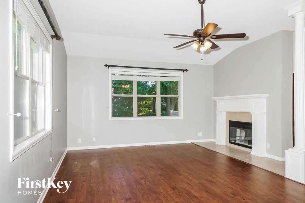 an empty living room with a fireplace and a ceiling fan