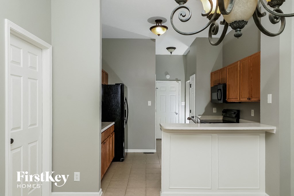 a kitchen with a white counter top and a black refrigerator