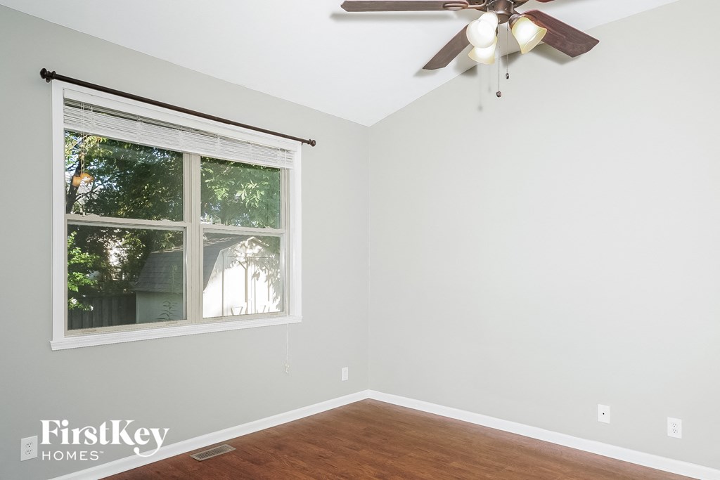 a bedroom with a large window and a ceiling fan