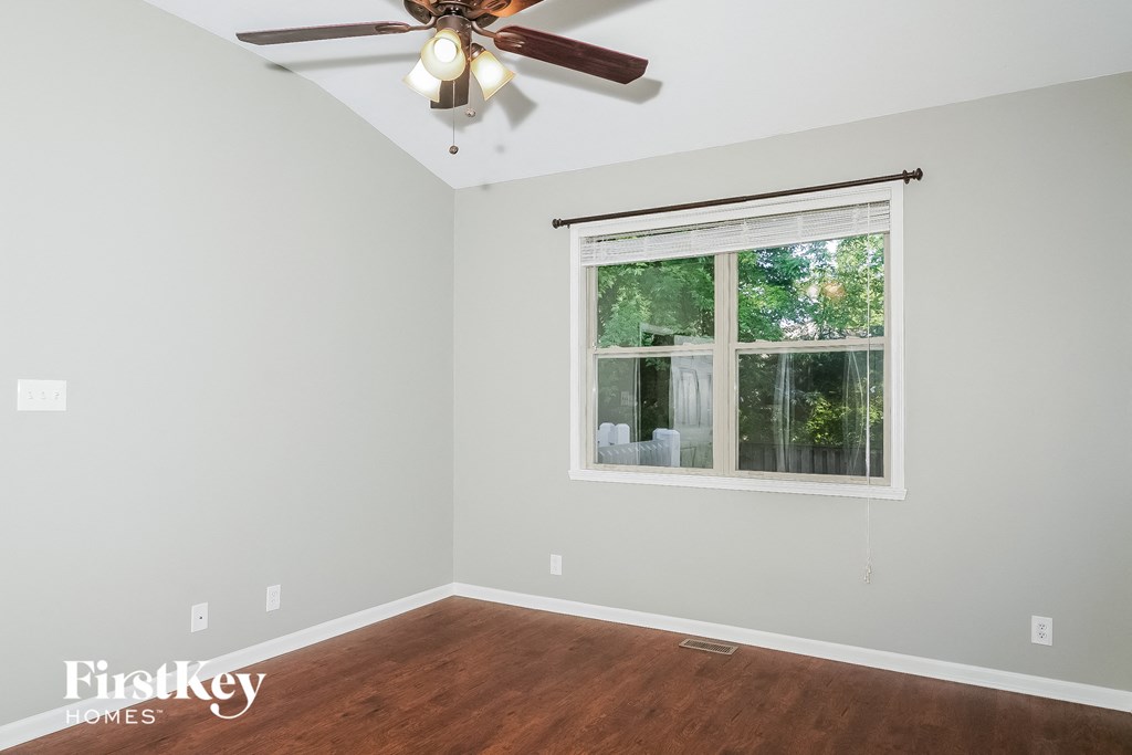 a bedroom with a large window and a ceiling fan