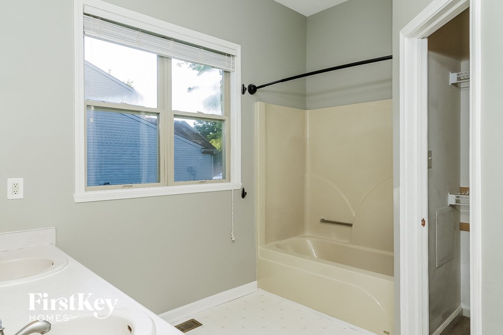 a bathroom with a tub and a sink and a window