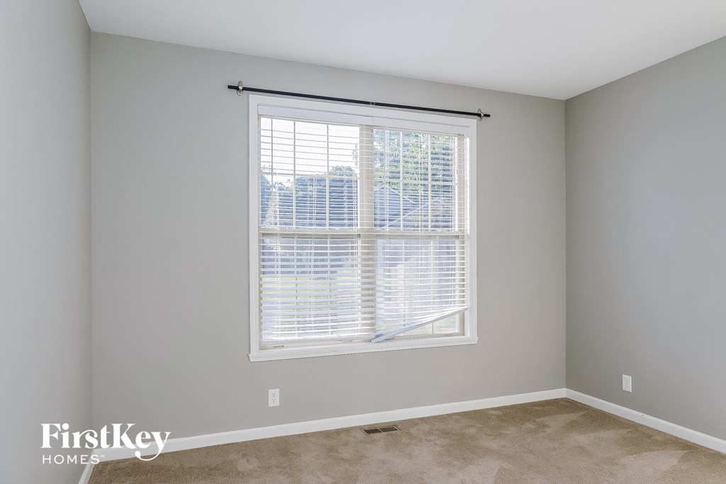 a bedroom with a large window and a carpeted floor