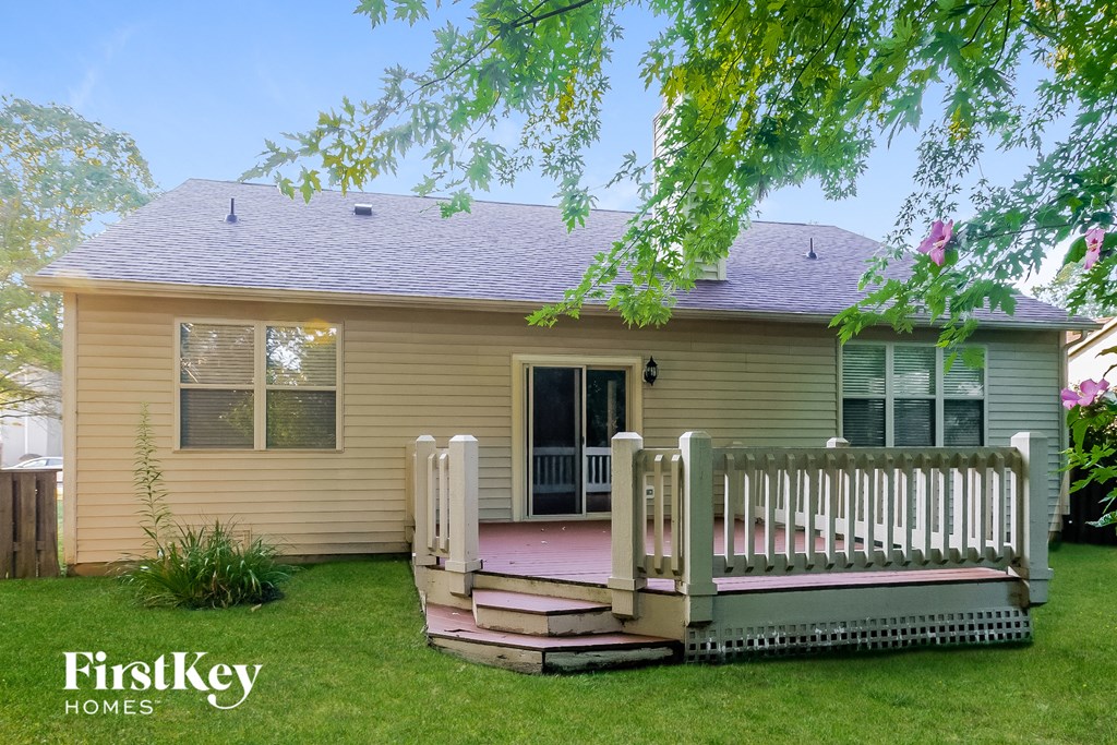 a yellow house with a porch and a white fence