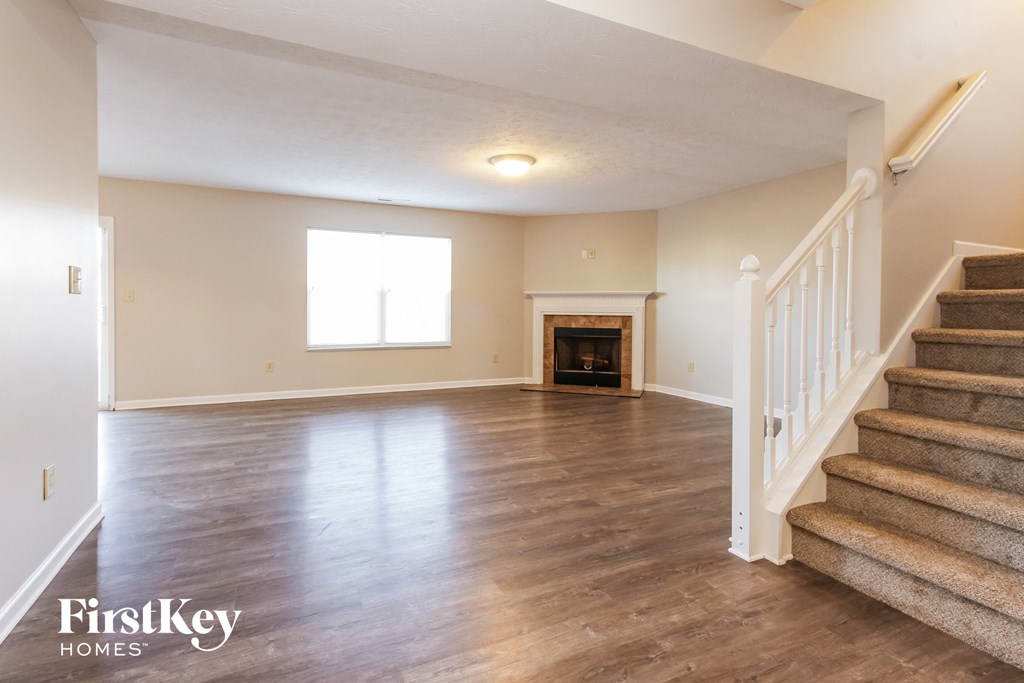 A spacious living room with a staircase leading to the upper floor.