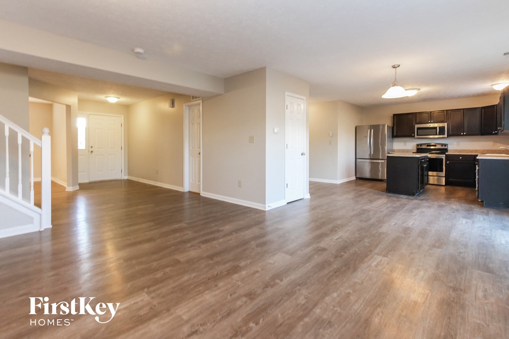 A spacious kitchen and living room with wooden floors and modern appliances.