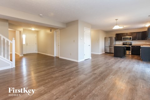 A spacious kitchen and living room with wooden floors and modern appliances.