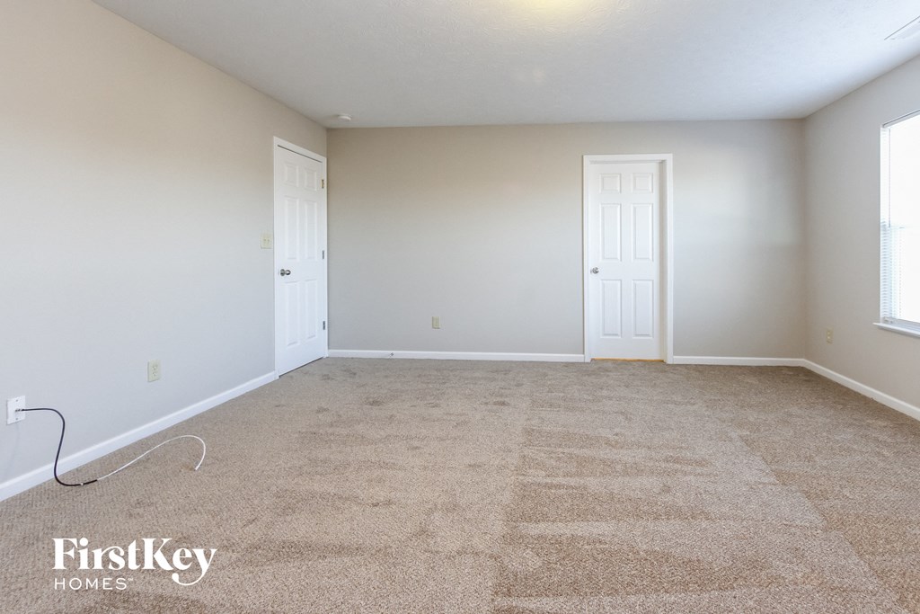 A carpeted room with two doors and a window.