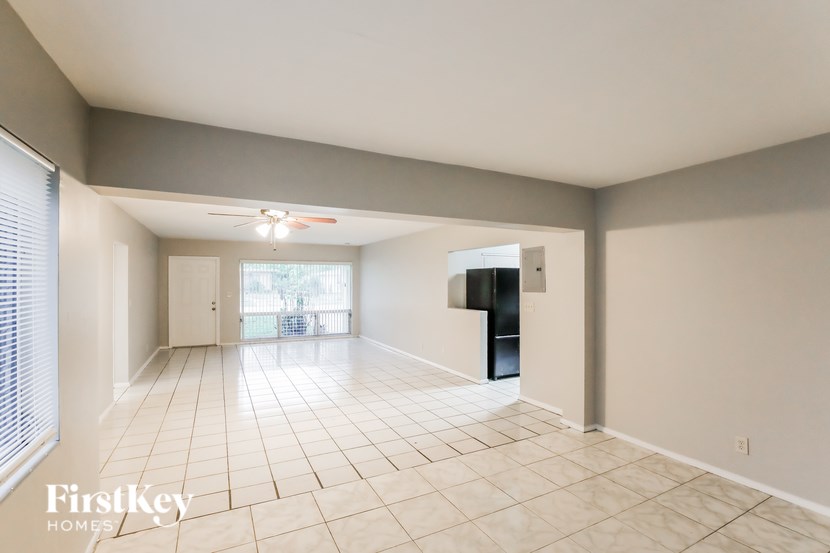 A spacious room with a ceiling fan and tiled flooring.