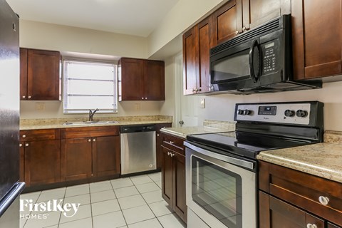 A kitchen with wooden cabinets and a black microwave above the stove.