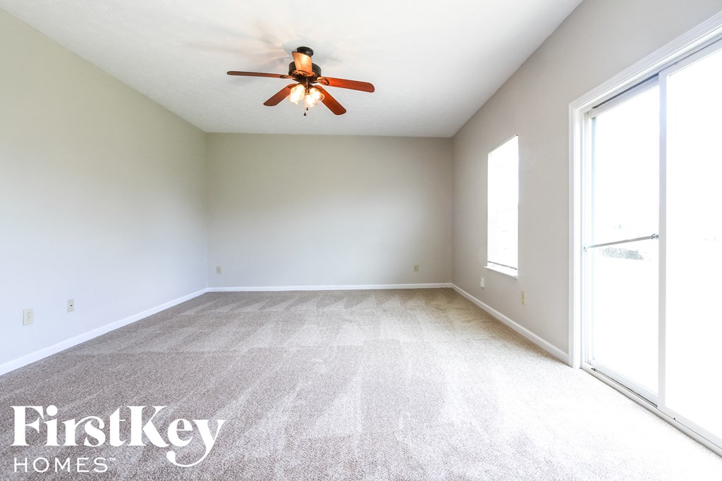 an empty room with a ceiling fan and large windows