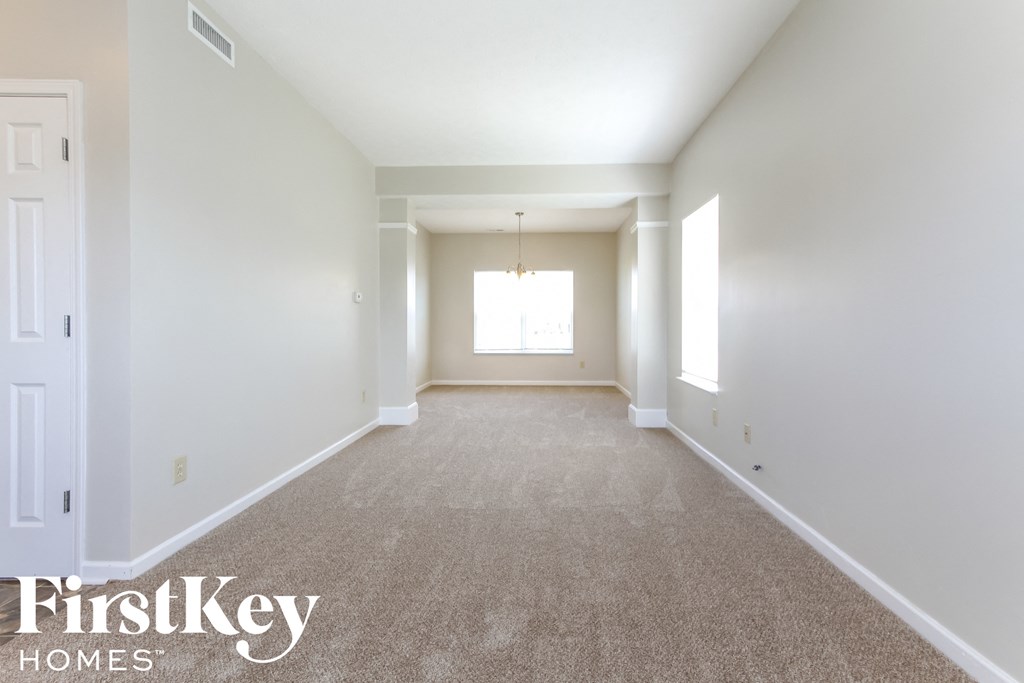 a empty living room with white walls and carpet