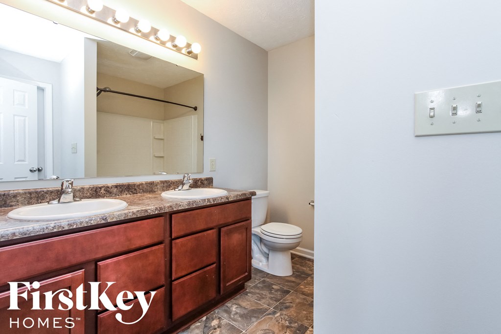 a bathroom with two sinks and a toilet and a mirror