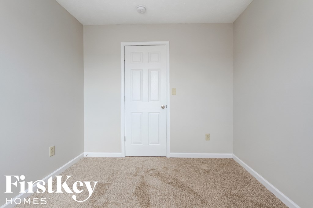 a blank white room with a white door and carpet