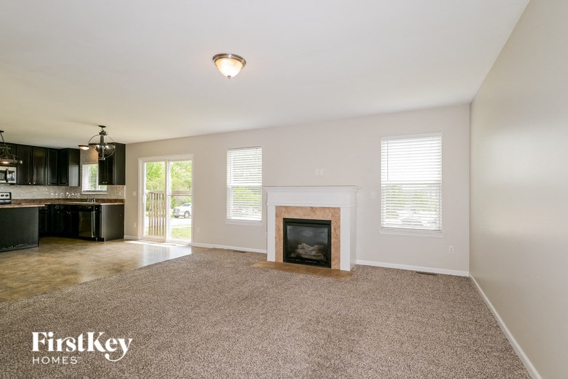 an empty living room with a fireplace and a kitchen