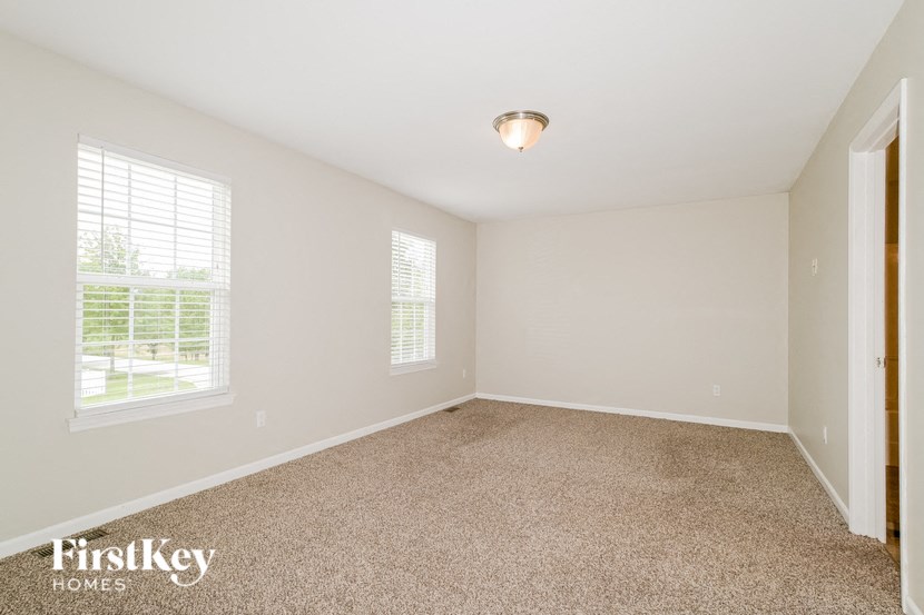 a bedroom with a carpeted floor and two windows