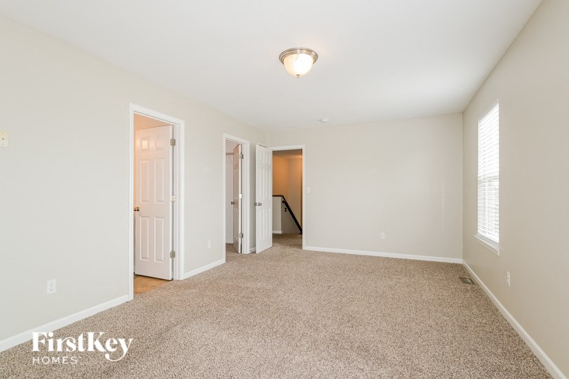 a spacious living room with carpet and a door to a hallway