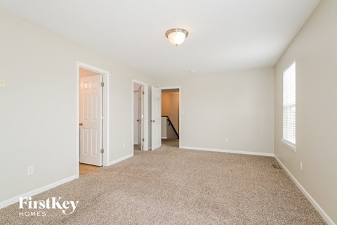 a spacious living room with carpet and a door to a hallway
