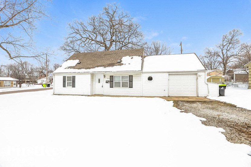 A white house with a snow-covered roof and a driveway.