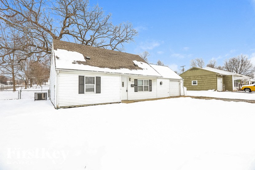 A white house with a snow covered ground.