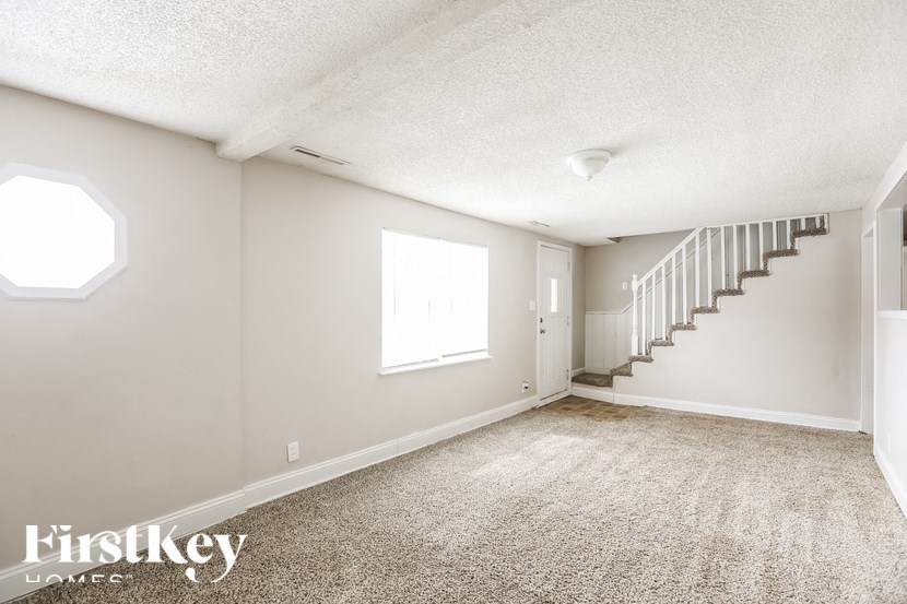 A spacious room with a staircase and a window.