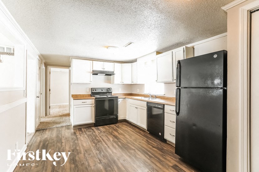A kitchen with black appliances and wooden floors.