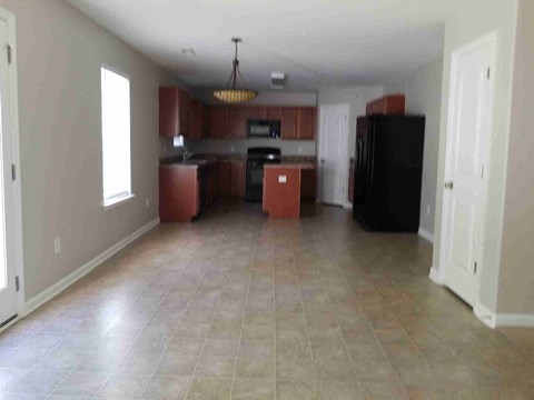 A kitchen with a black refrigerator and brown cabinets.
