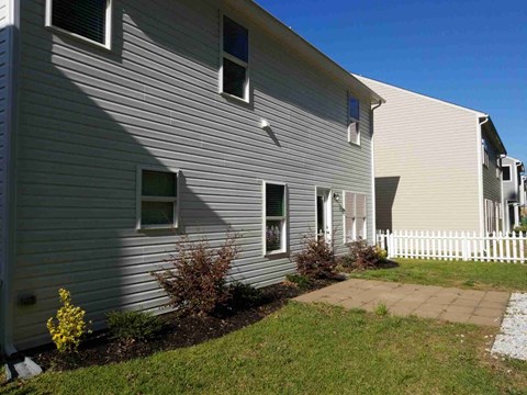 A house with a white picket fence and a small garden in front.