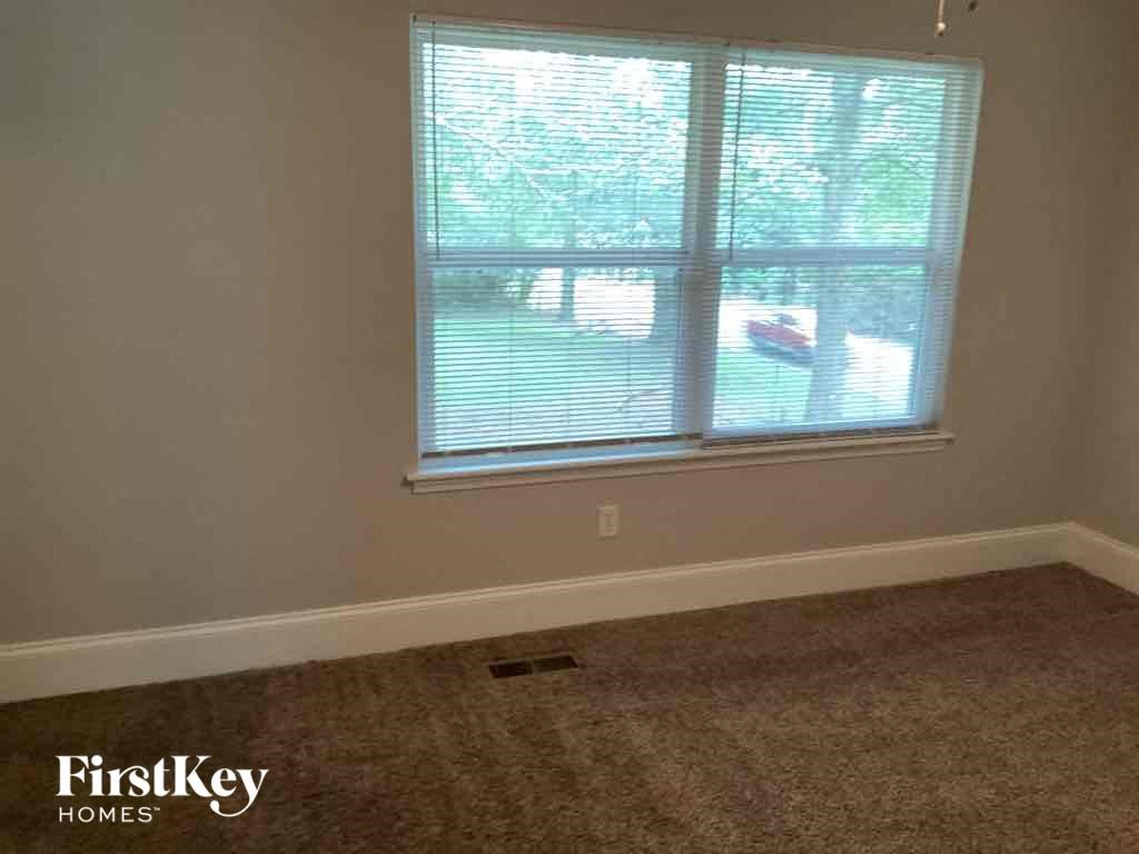 A room with a carpeted floor and a window with blinds.
