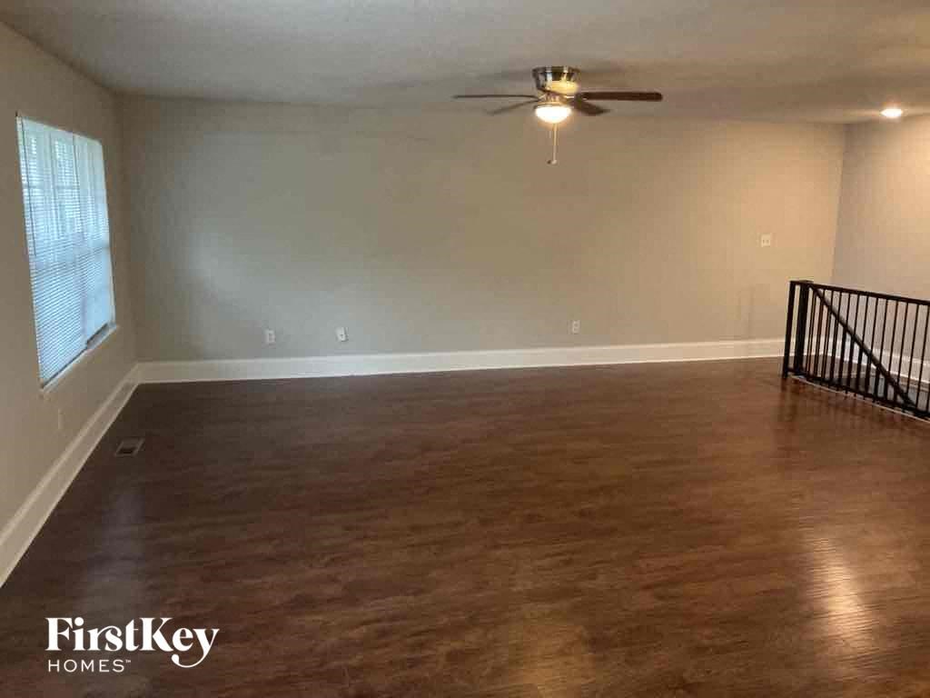 A spacious room with wooden flooring and a ceiling fan.