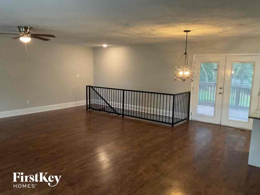 Empty room with a wooden floor and a ceiling fan.