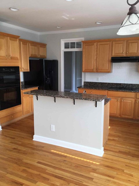 A kitchen with wooden cabinets and a black fridge.