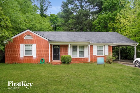 a small brick house with a yard and a chair in front of it