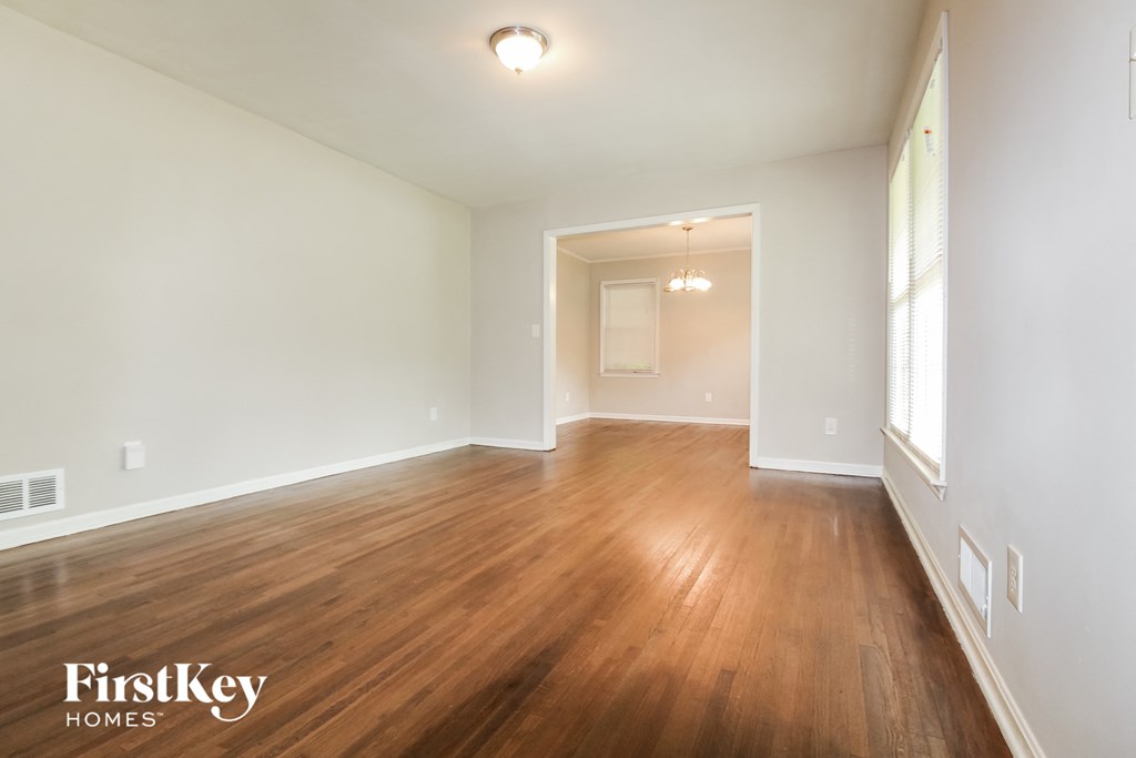 an empty living room with wood flooring and white walls