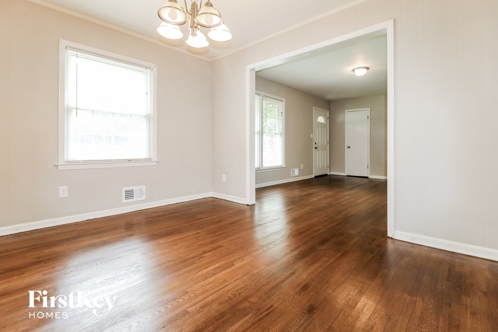 an empty living room with wood floors and white walls